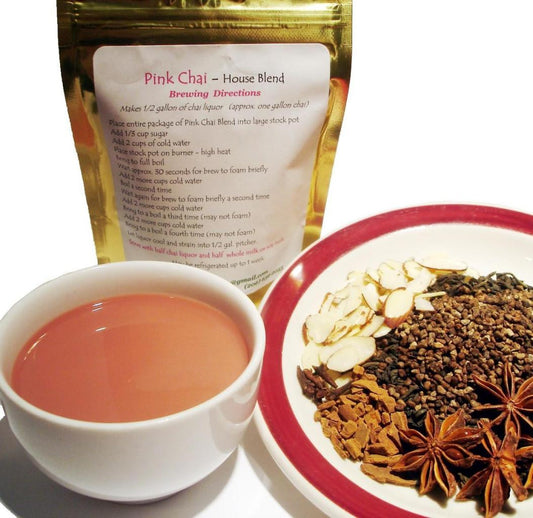 Pink Chai tea blend- loose spices on a dish, a small white cup of steeped tea, Pink Chai blend in gold packaging